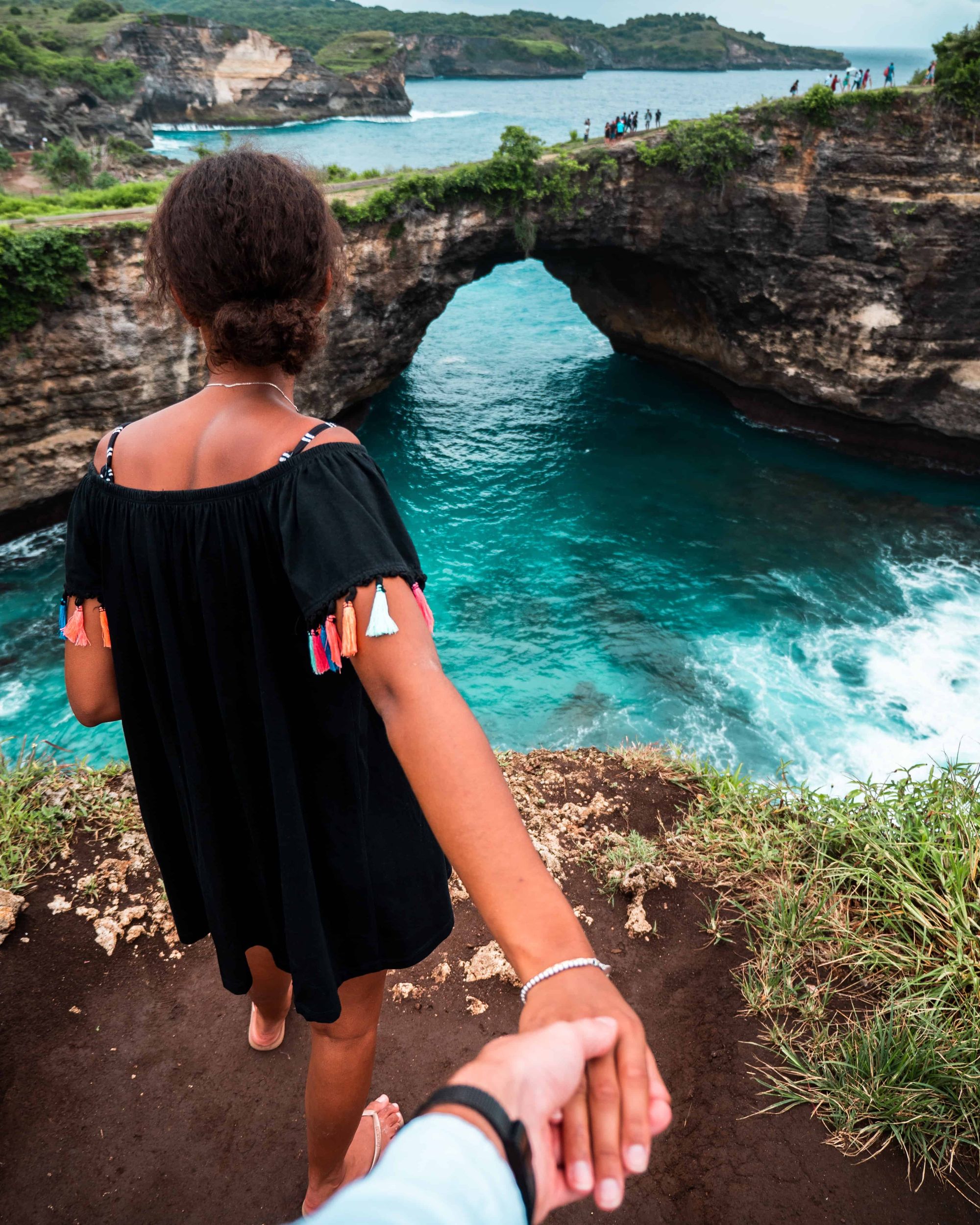 Photo of a woman looking at the ocean holding a man's hand